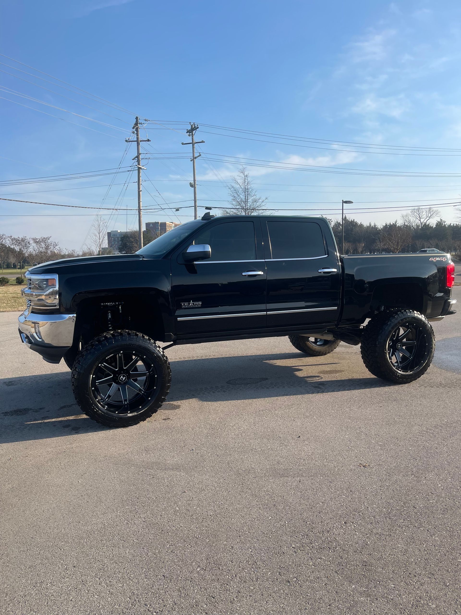 Black lifted pickup truck parked outdoors on a sunny day.