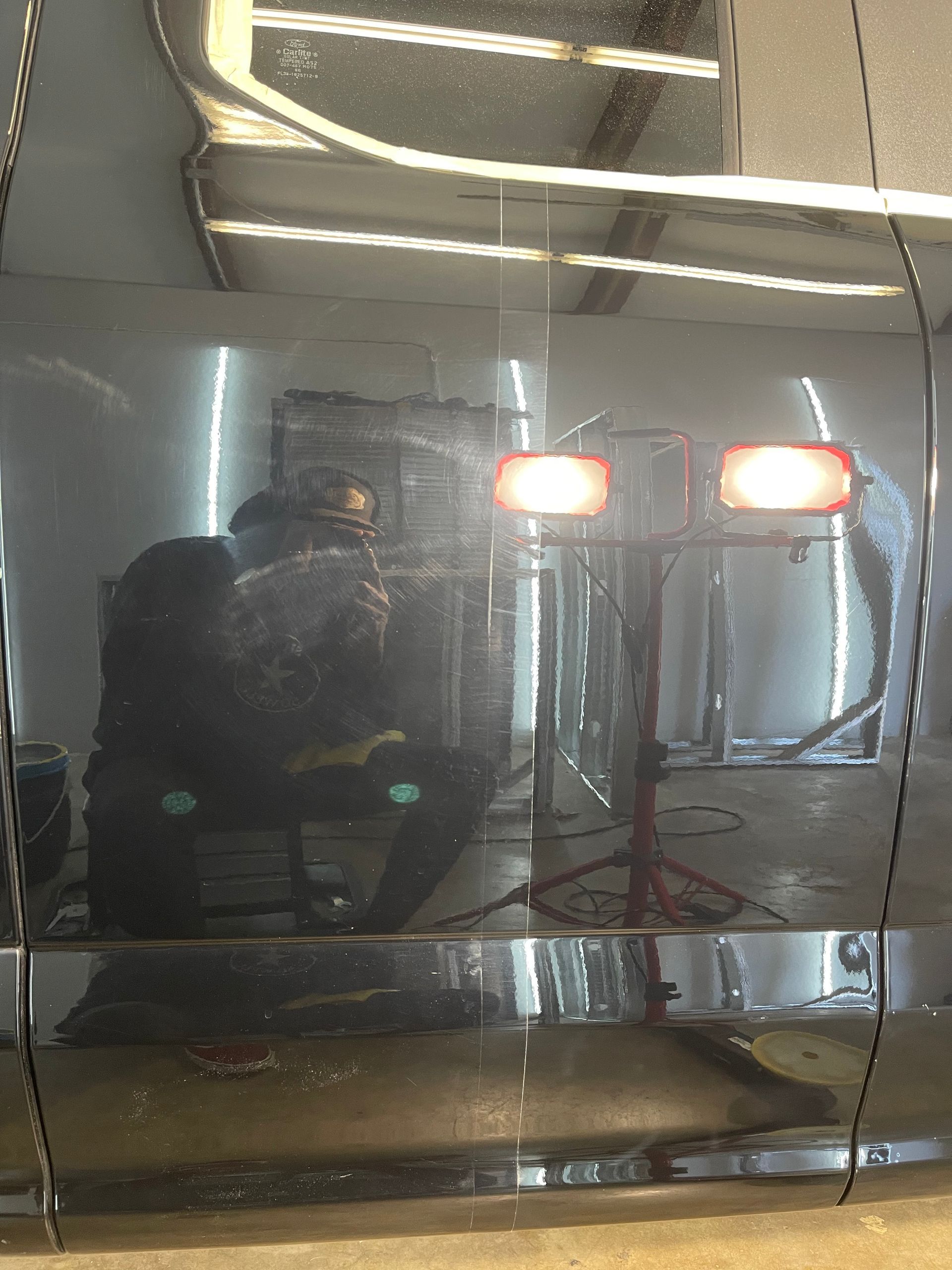 Reflection of a person with two lights in a shiny, metallic surface.