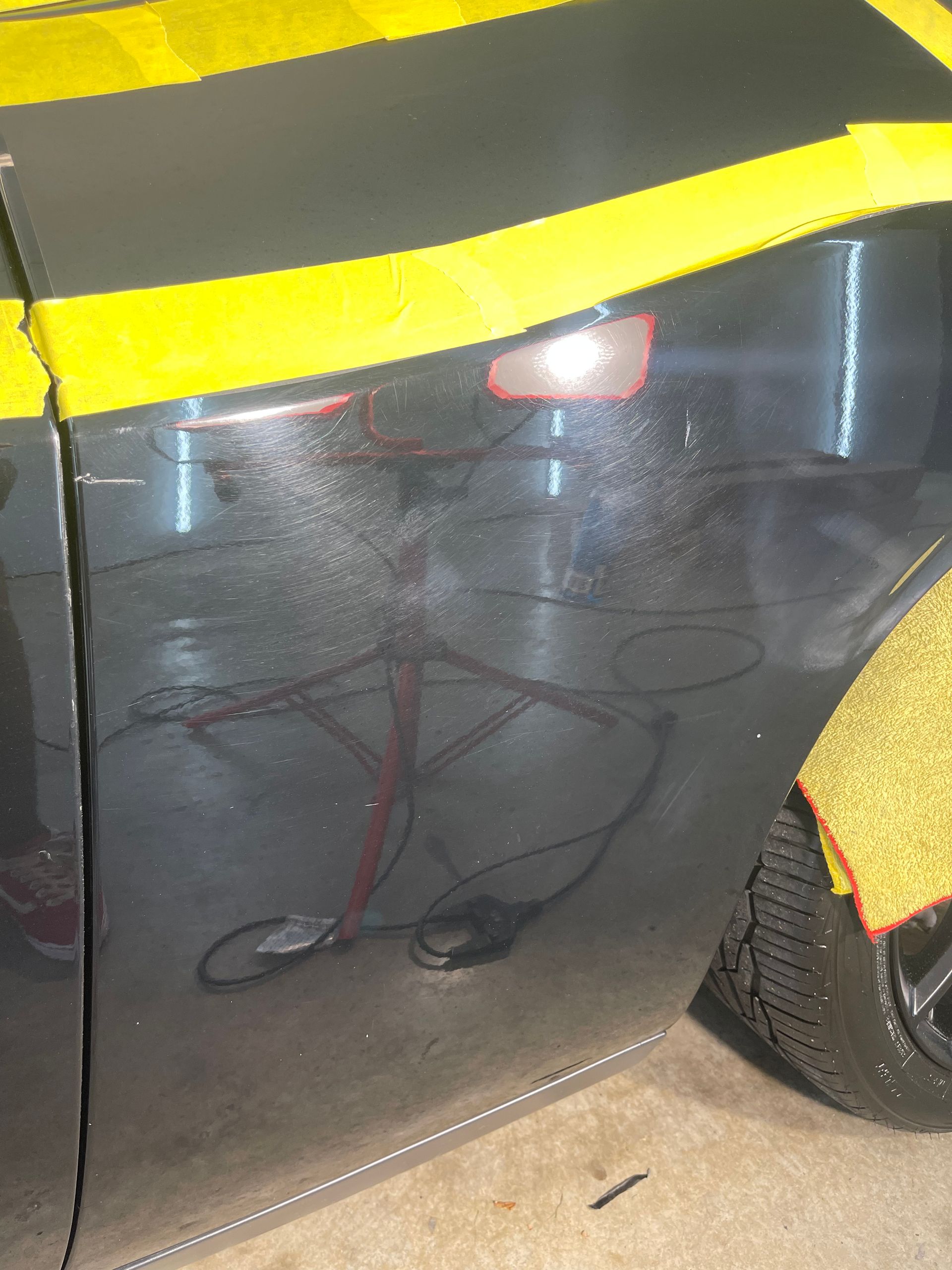 Car door with masking tape, showing a dent repair in progress.