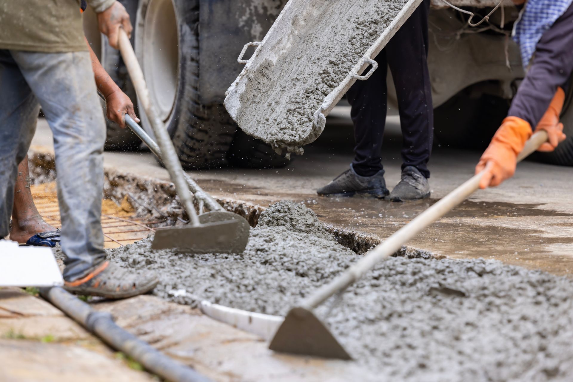 A group of construction workers are pouring concrete on a sidewalk.