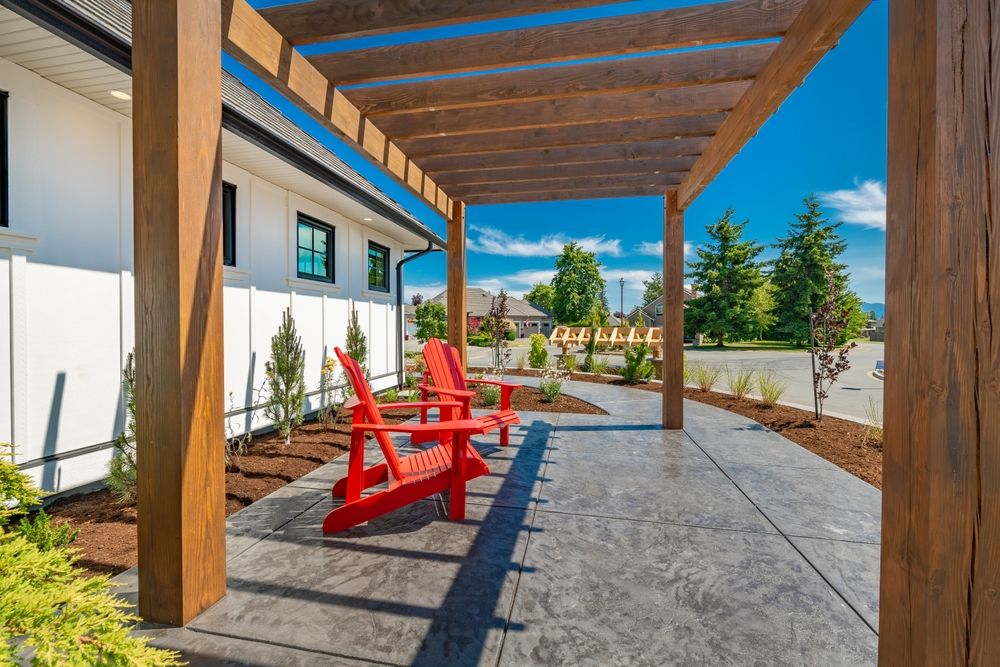 A patio with red chairs under a wooden pergola.