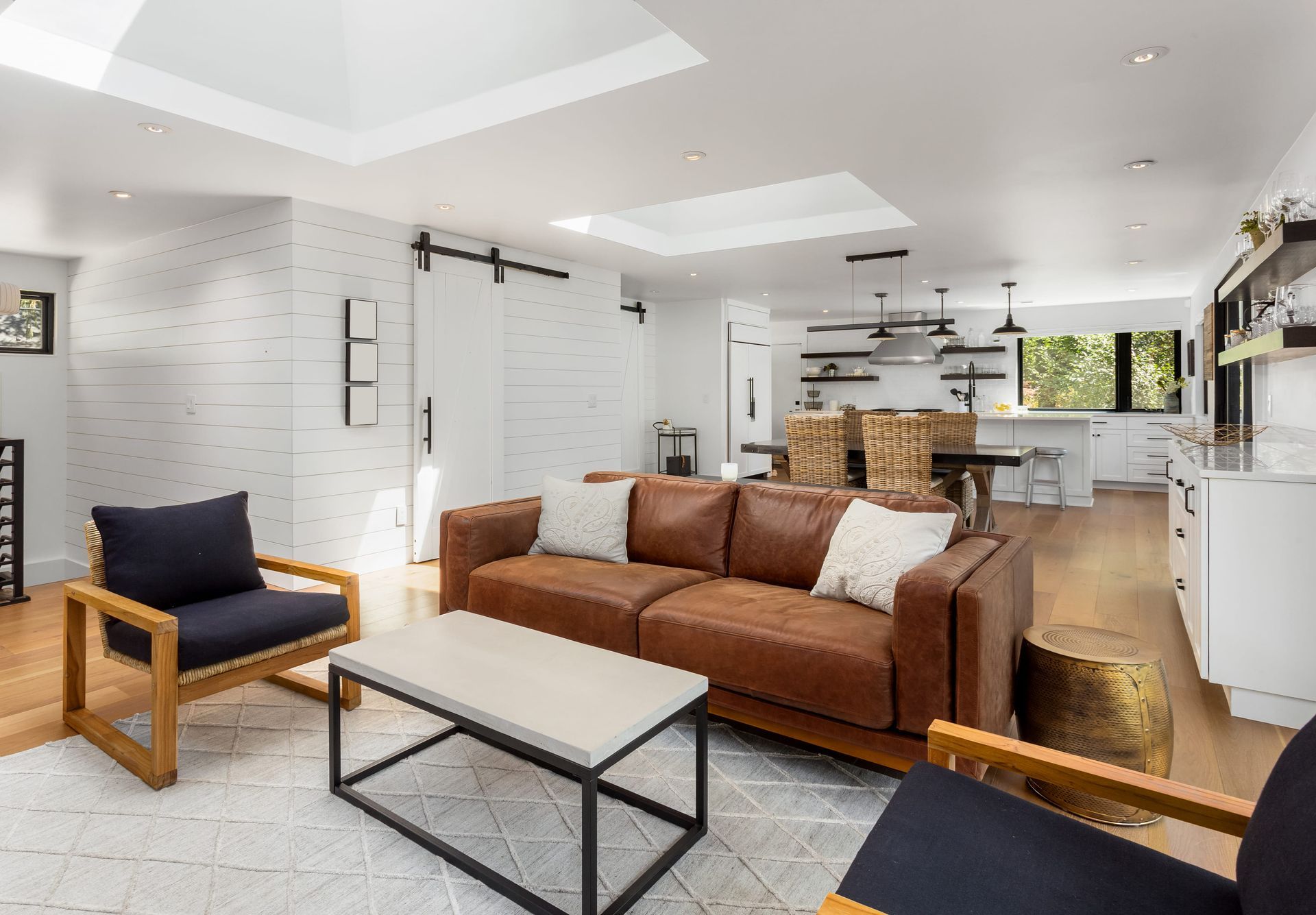 Modern living room with leather sofa, accent chairs, and light wood floors.