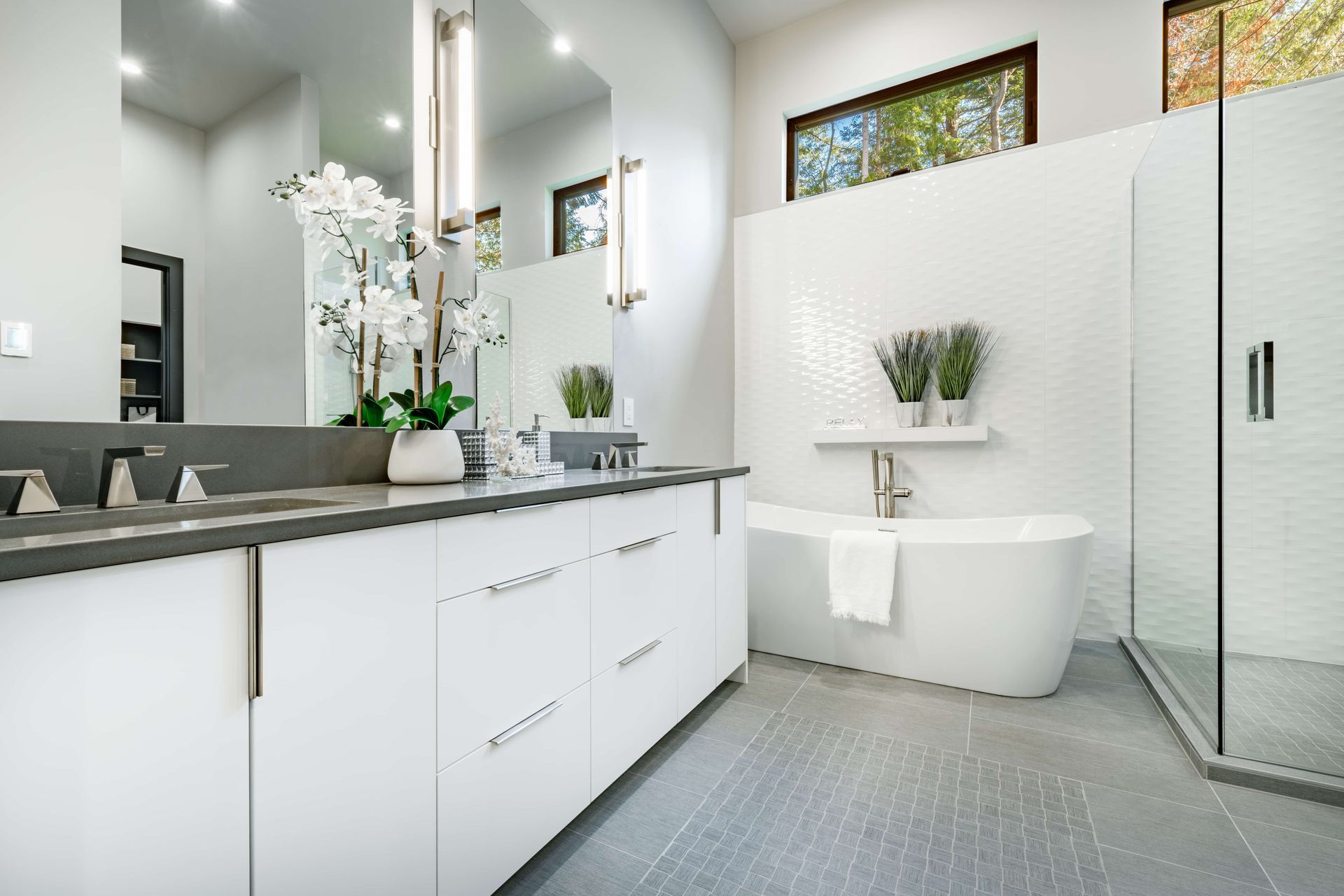 Modern white bathroom with double sink vanity, soaking tub, and shower.