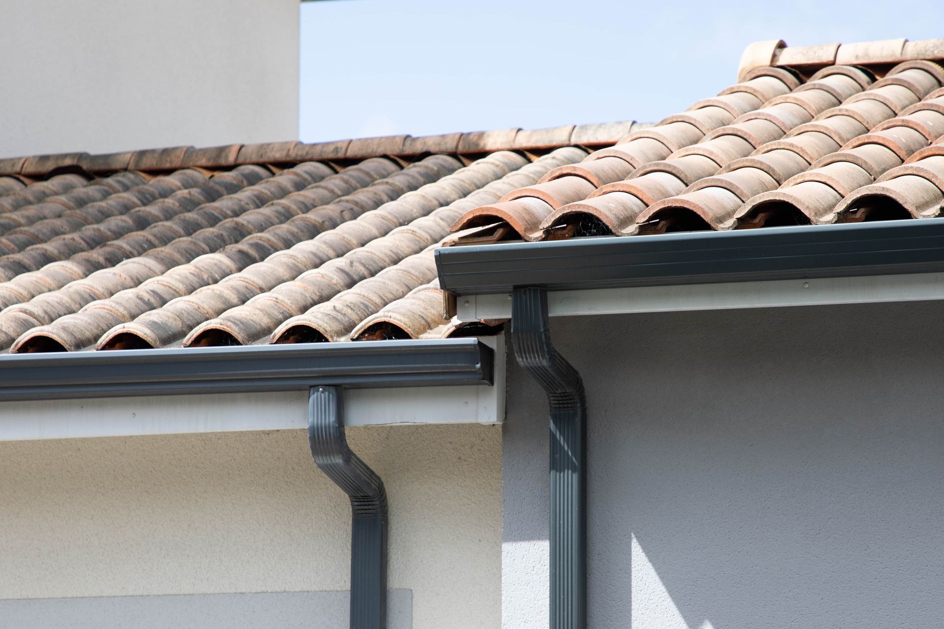 Dark gray gutters along the edge of a tan tile roof.