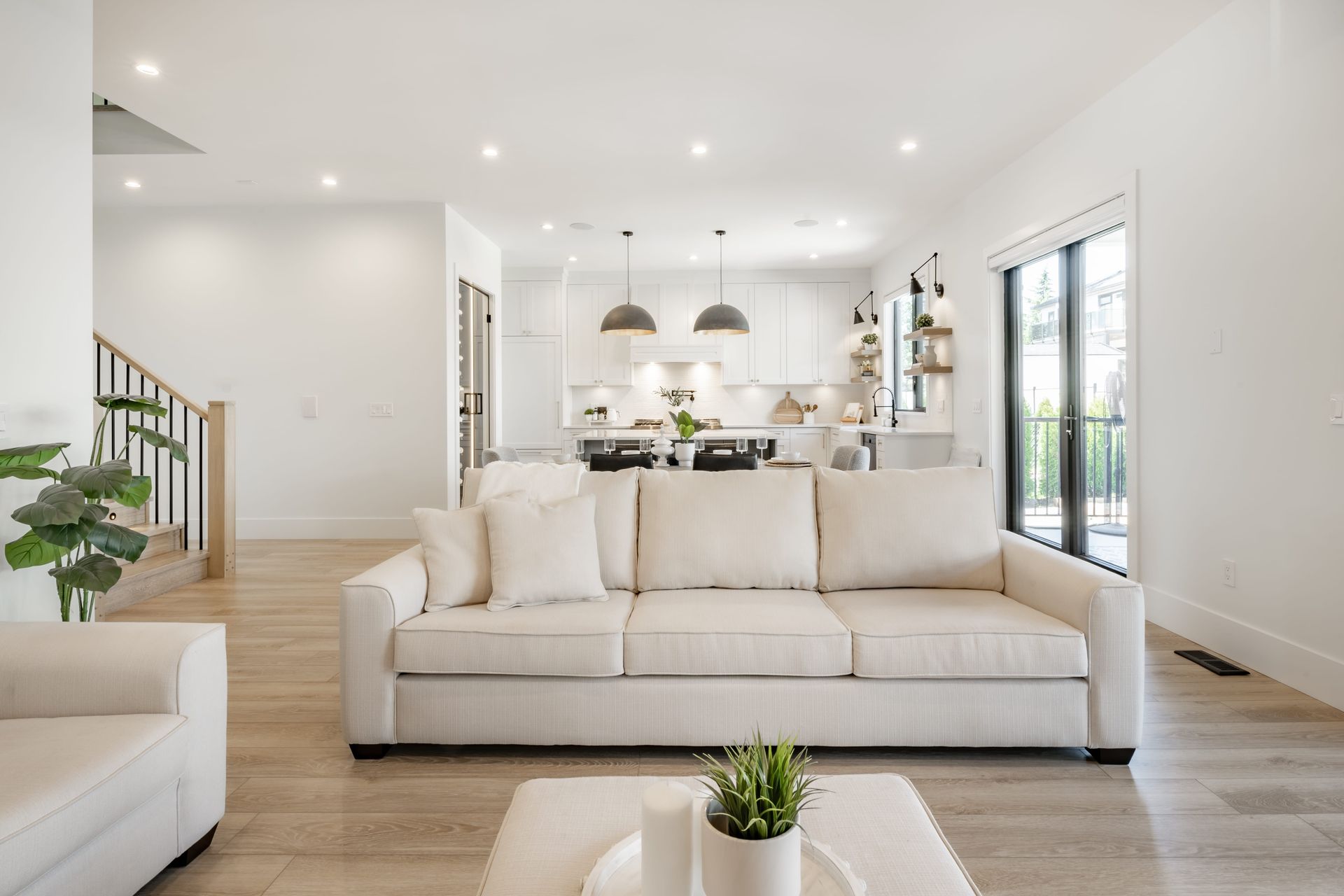 Bright living room with white walls, light wood floors, and a cream-colored sofa.