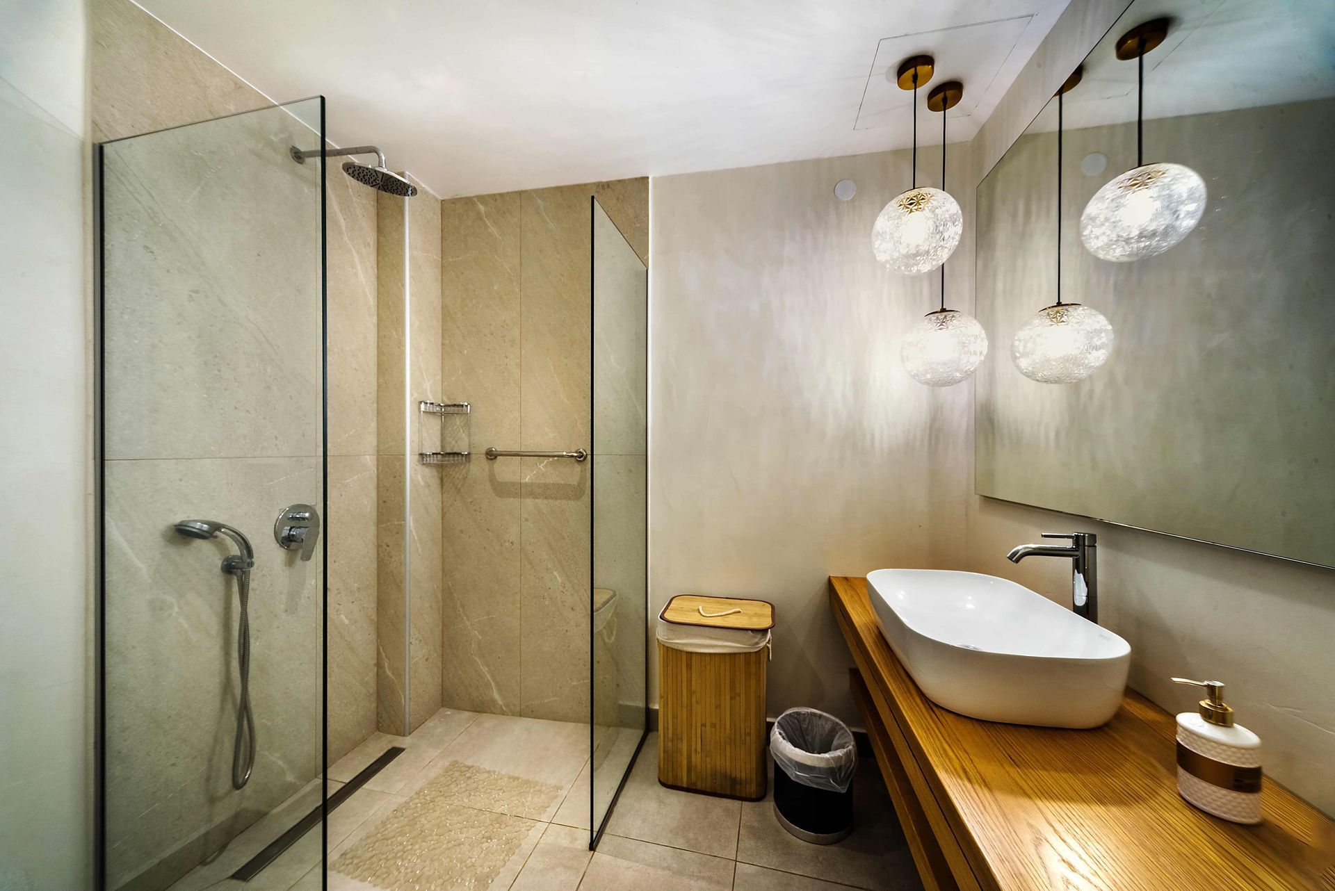 Bathroom with glass shower, modern sink on wood counter, and decorative pendant lights.