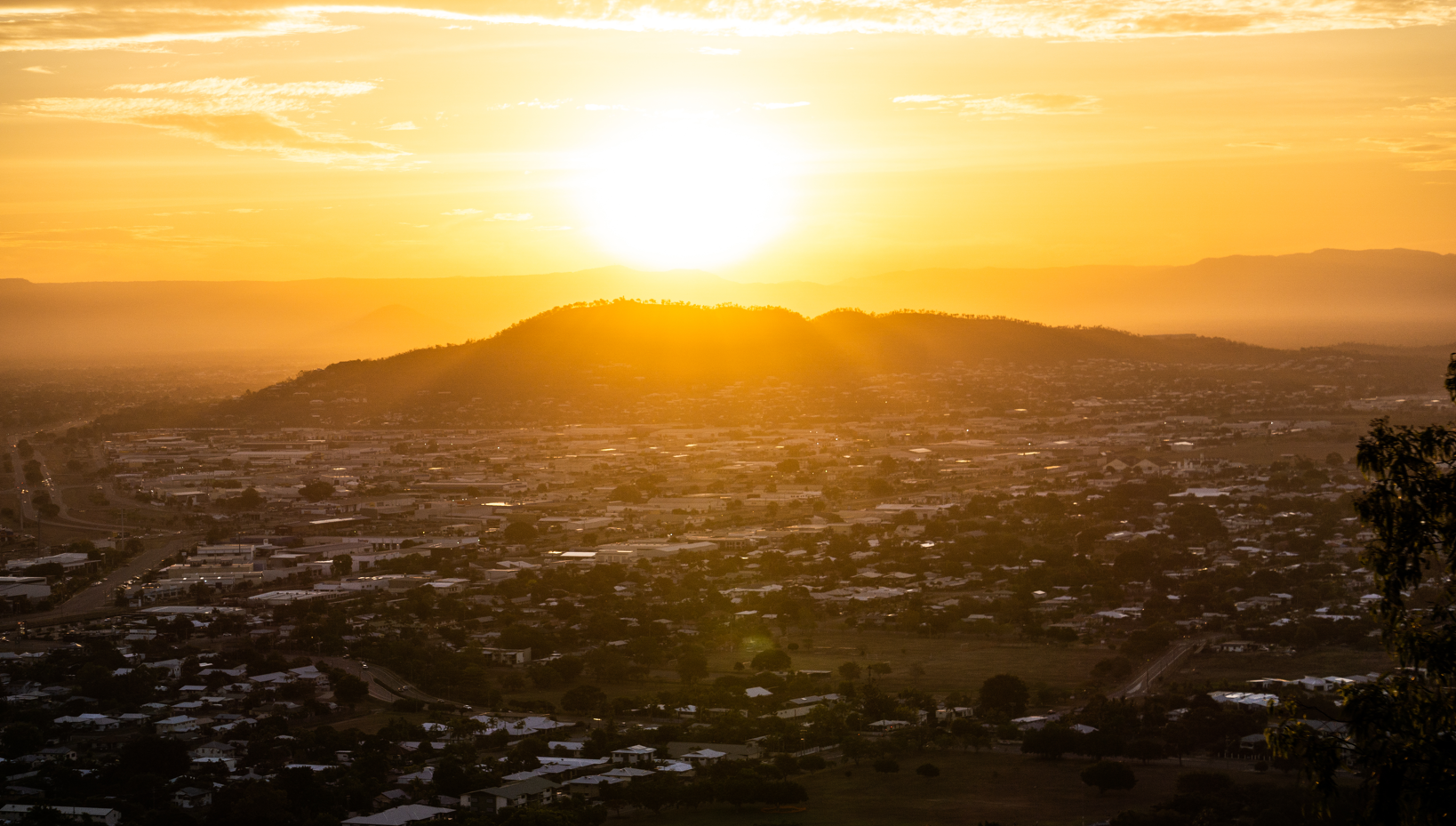 The Sun is Setting Over a City With Mountains in the Background — Gutterpro Townsville In Mt Louisa, QLD