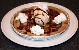 Chocolate pie topped with vanilla ice cream and whipped cream on a white plate