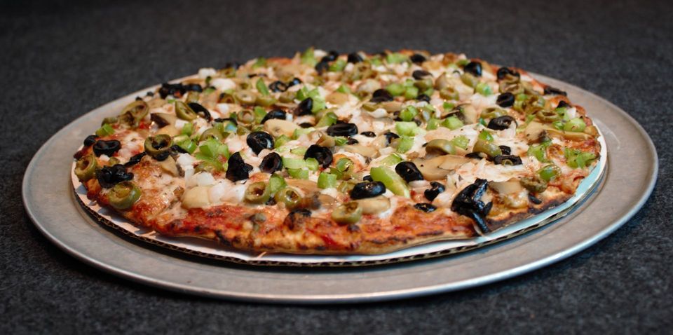 A large pizza topped with olives, mushrooms, and cheese on a white plate