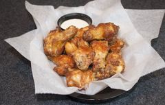 Basket of golden fried chicken bites lined with white paper on a dark table