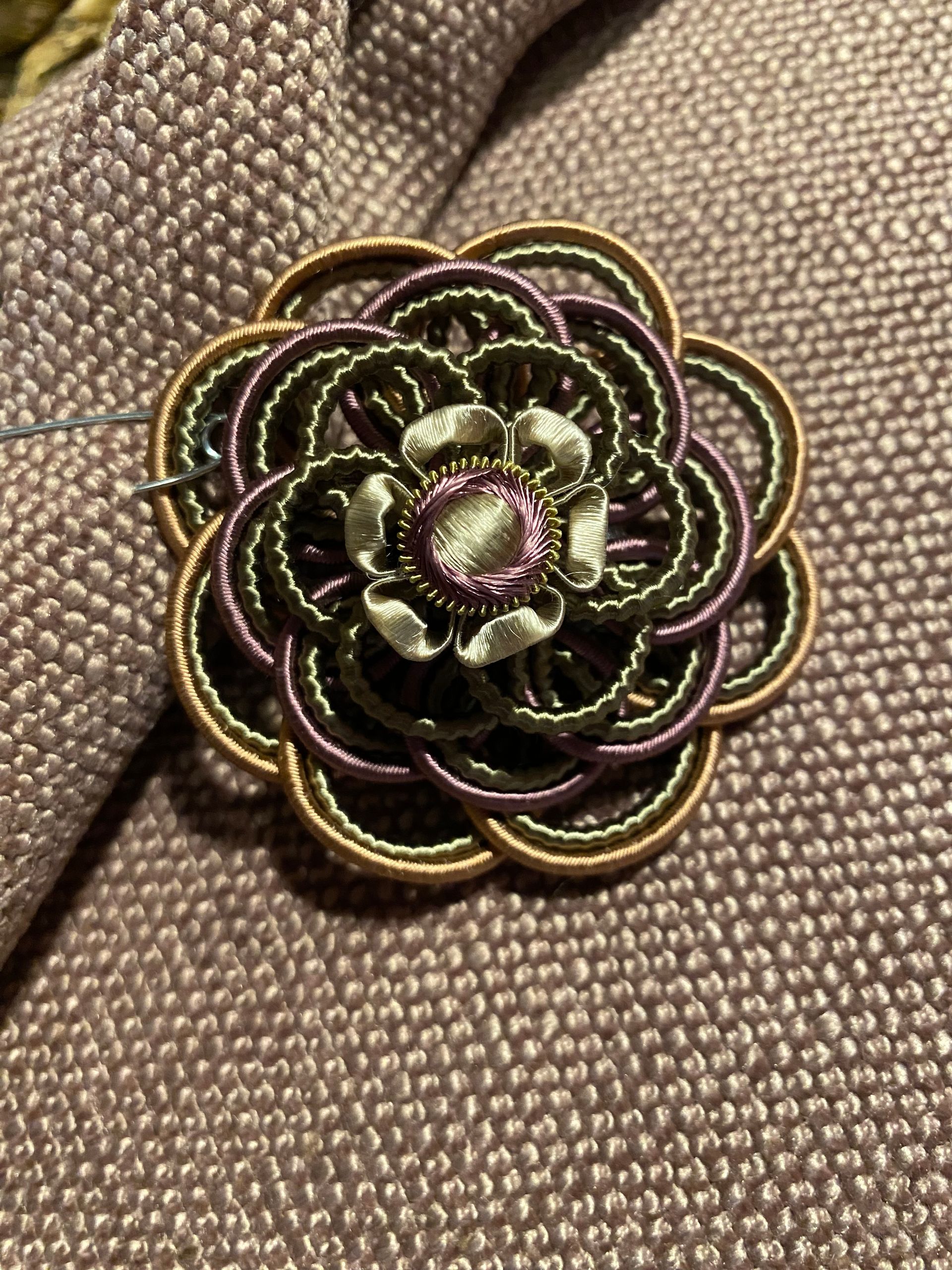 A brooch in the shape of a flower is sitting on a piece of fabric.