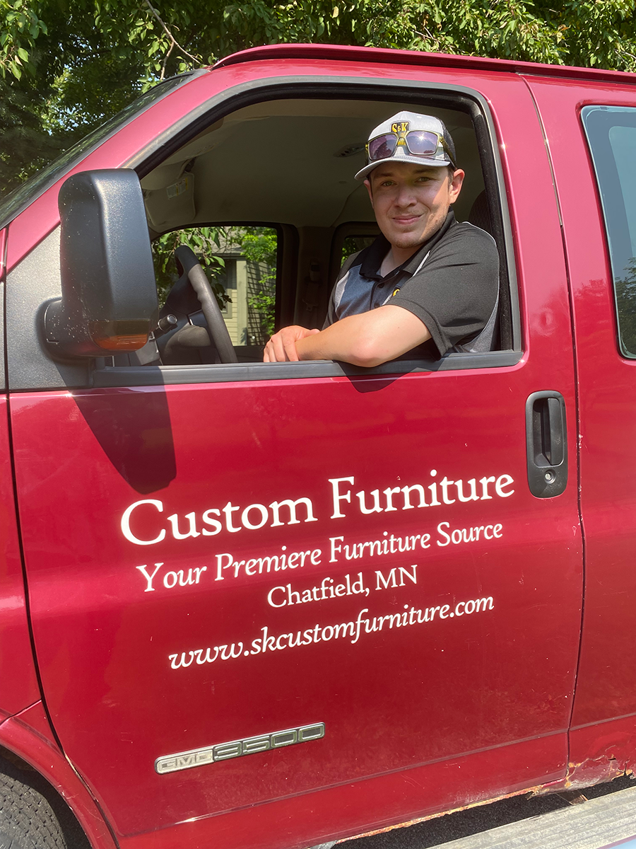 A man is sitting in the driver 's seat of a red van.