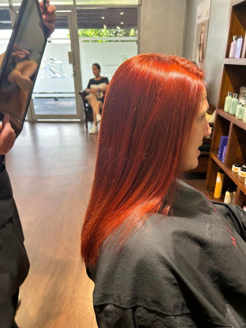 A woman with red hair is getting her hair cut at a salon