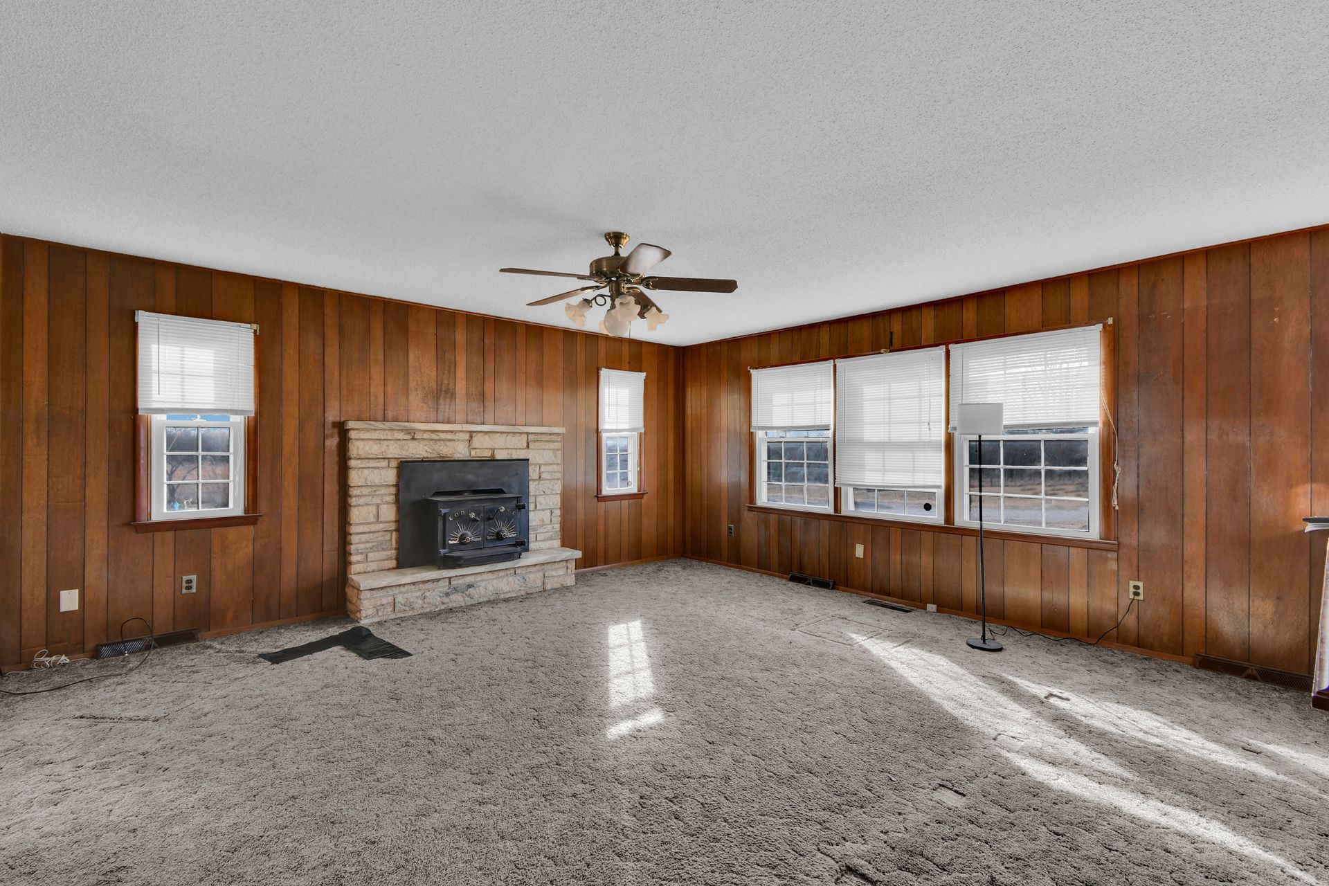 An empty living room with a vaulted ceiling and a ceiling fan.