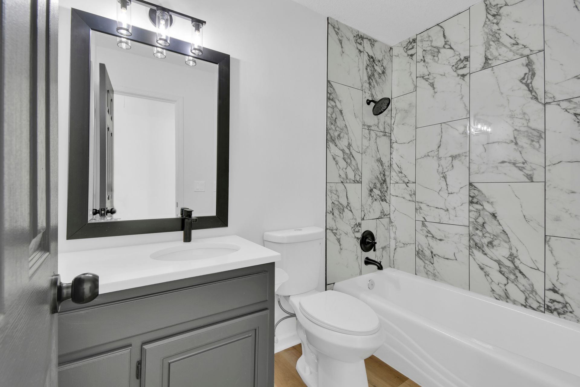 A bathroom with a toilet , sink , mirror and bathtub.