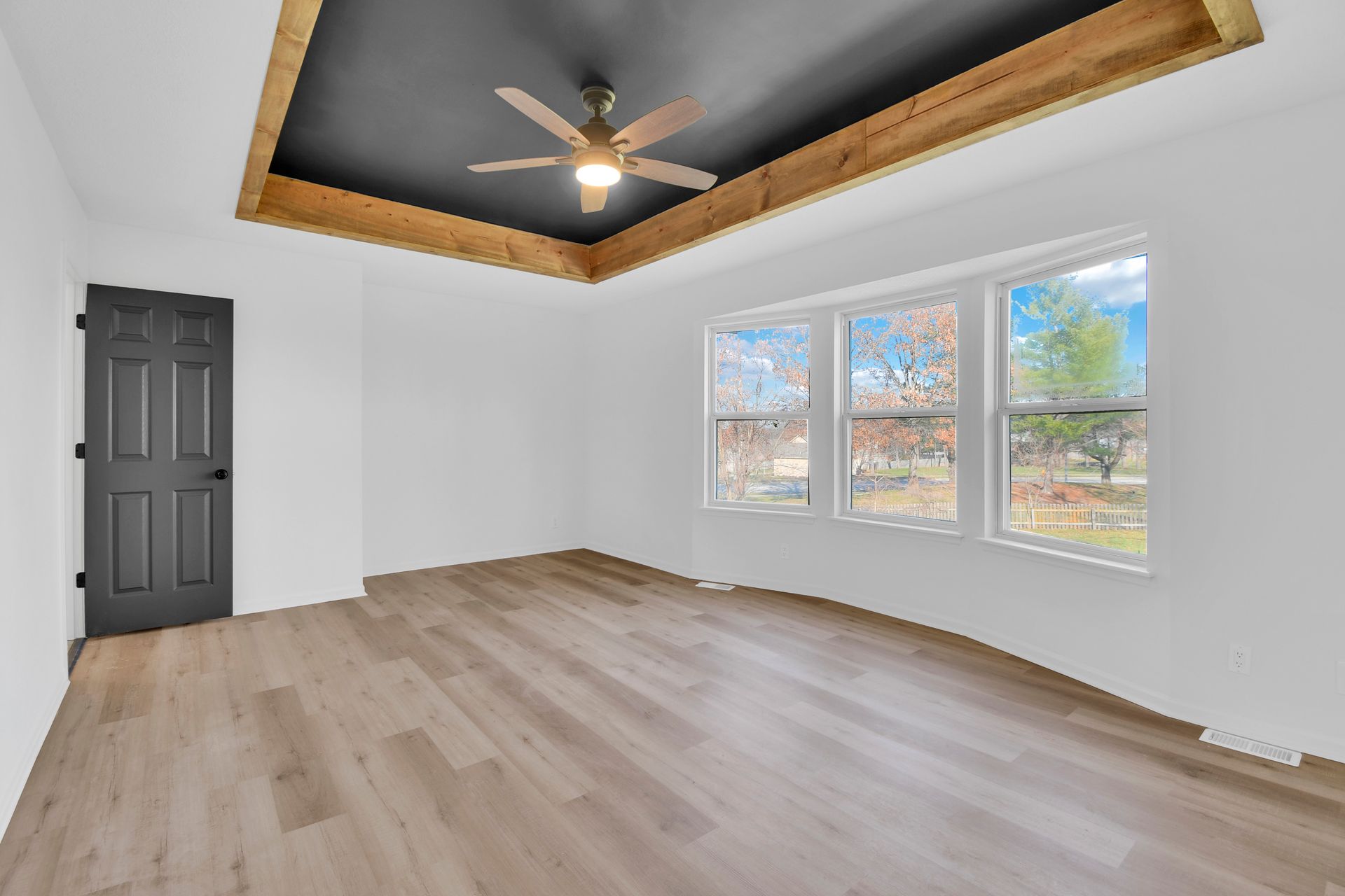 An empty room with hardwood floors and a ceiling fan.