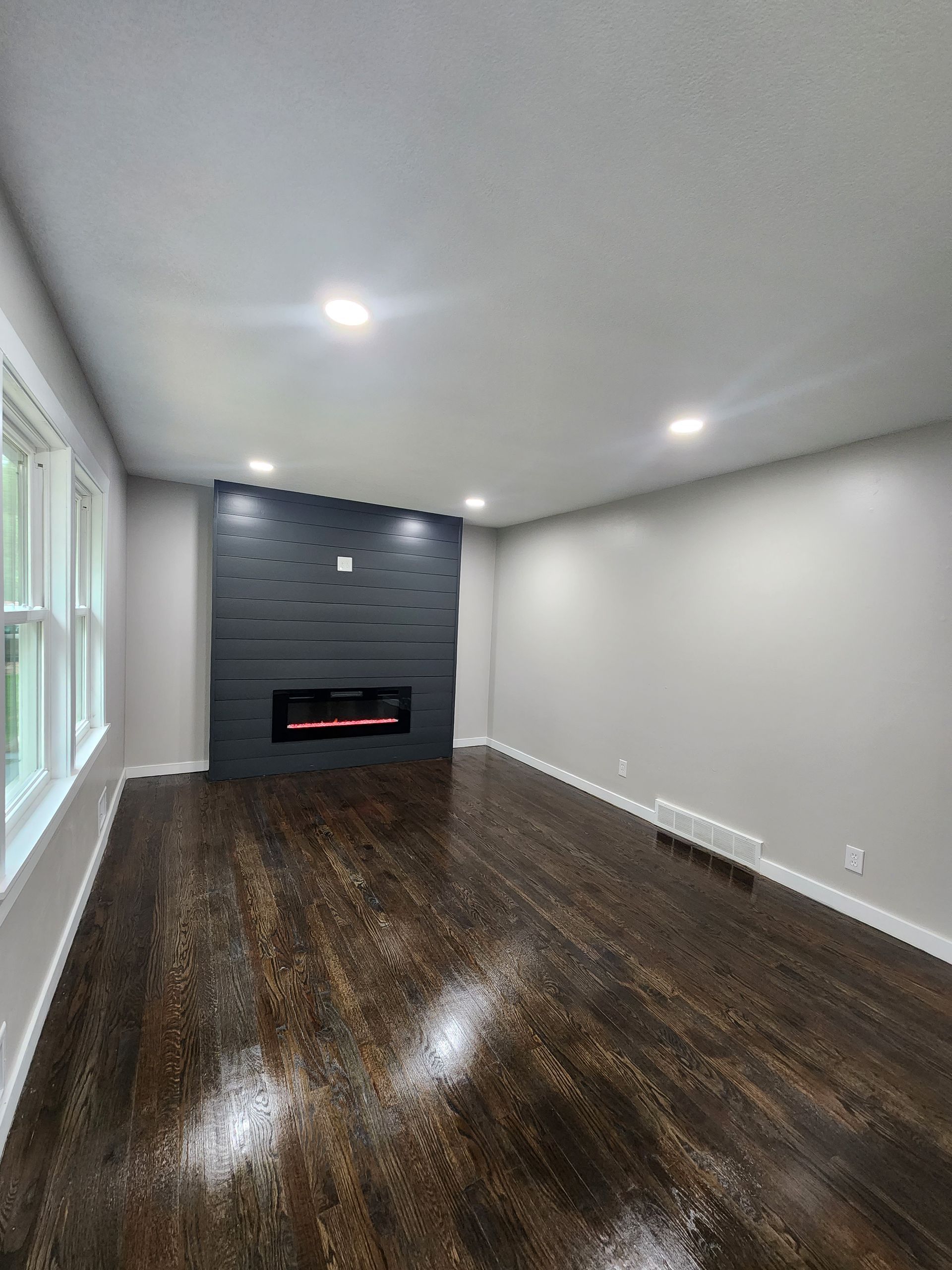 An empty living room with hardwood floors and a fireplace.