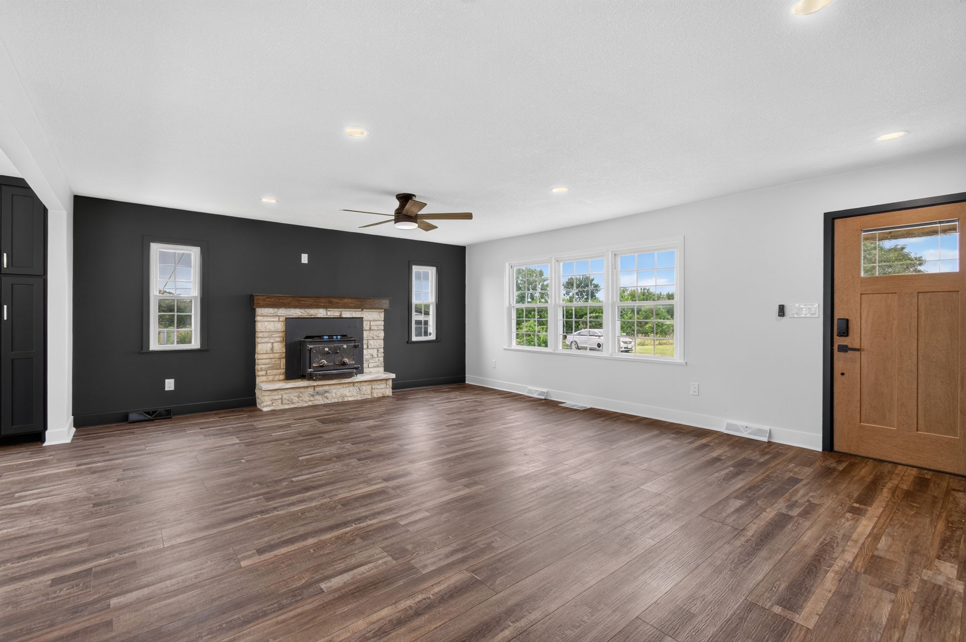An empty living room with hardwood floors and a vaulted ceiling.