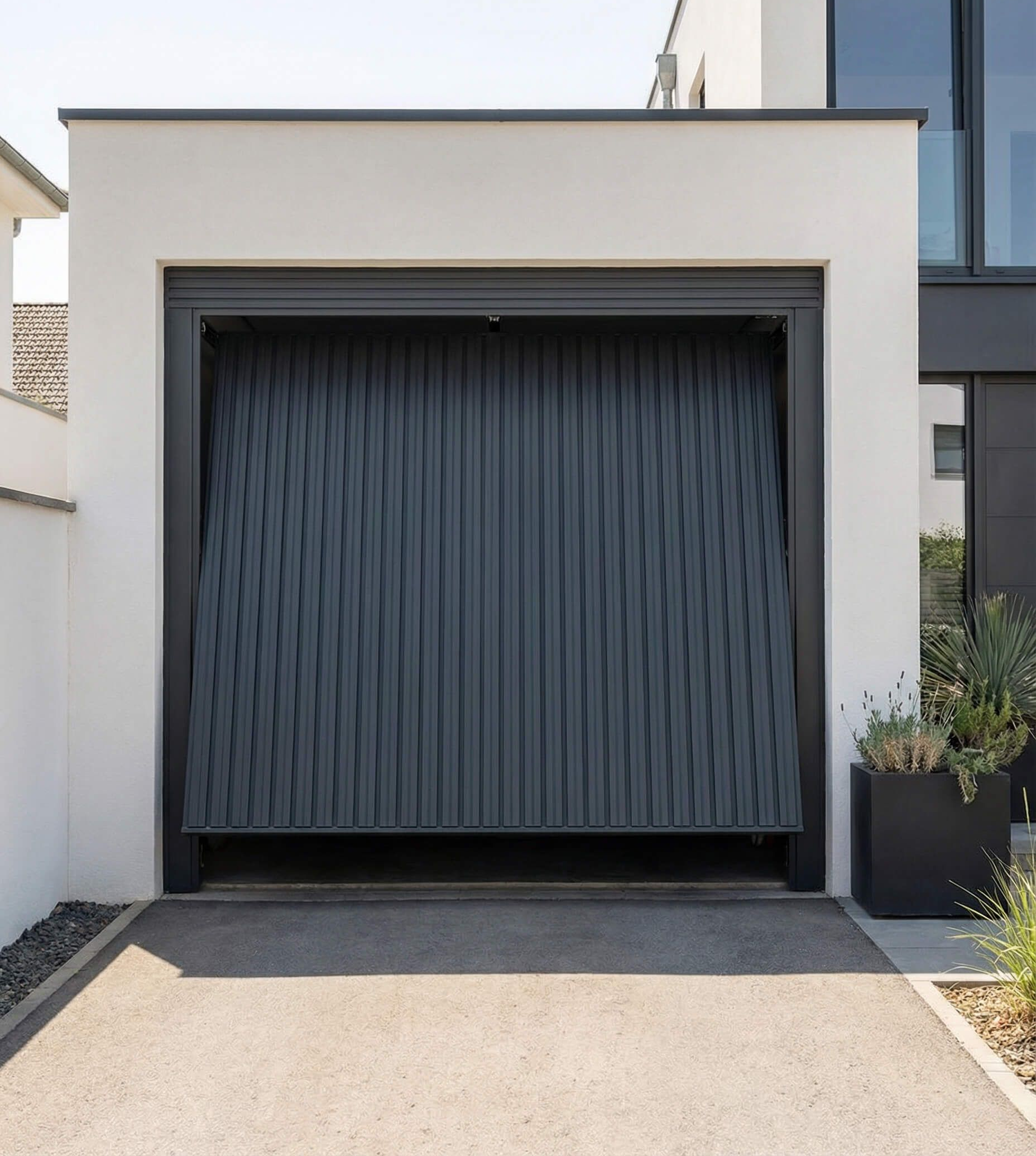 Puerta de garaje de lamas verticales de color gris abierta en una fachada de edificio de color blanco con entrada pavimentada.