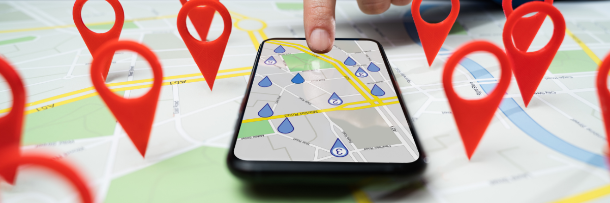A person is pointing at a cell phone with a map on it.