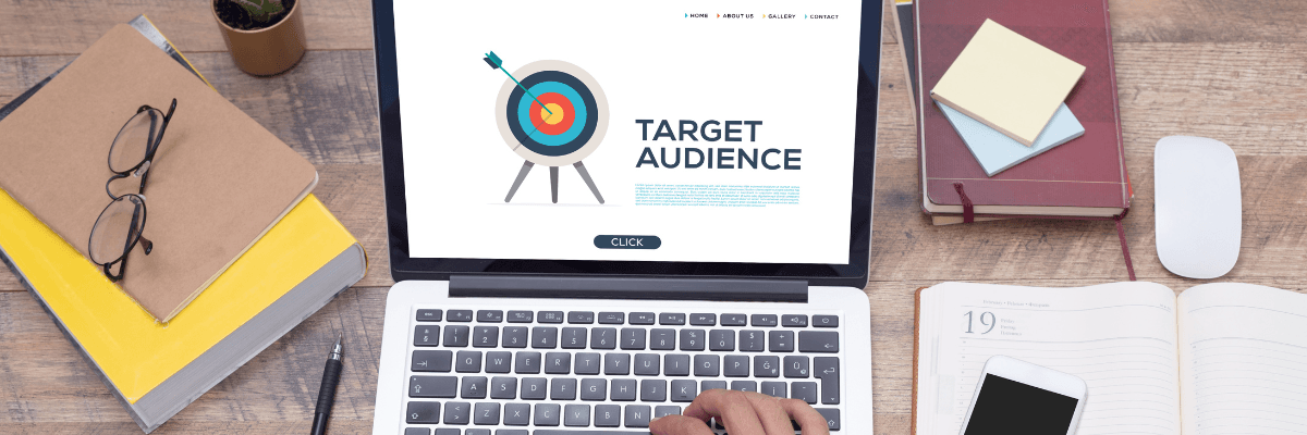 A person is typing on a laptop computer with a target audience on the screen.