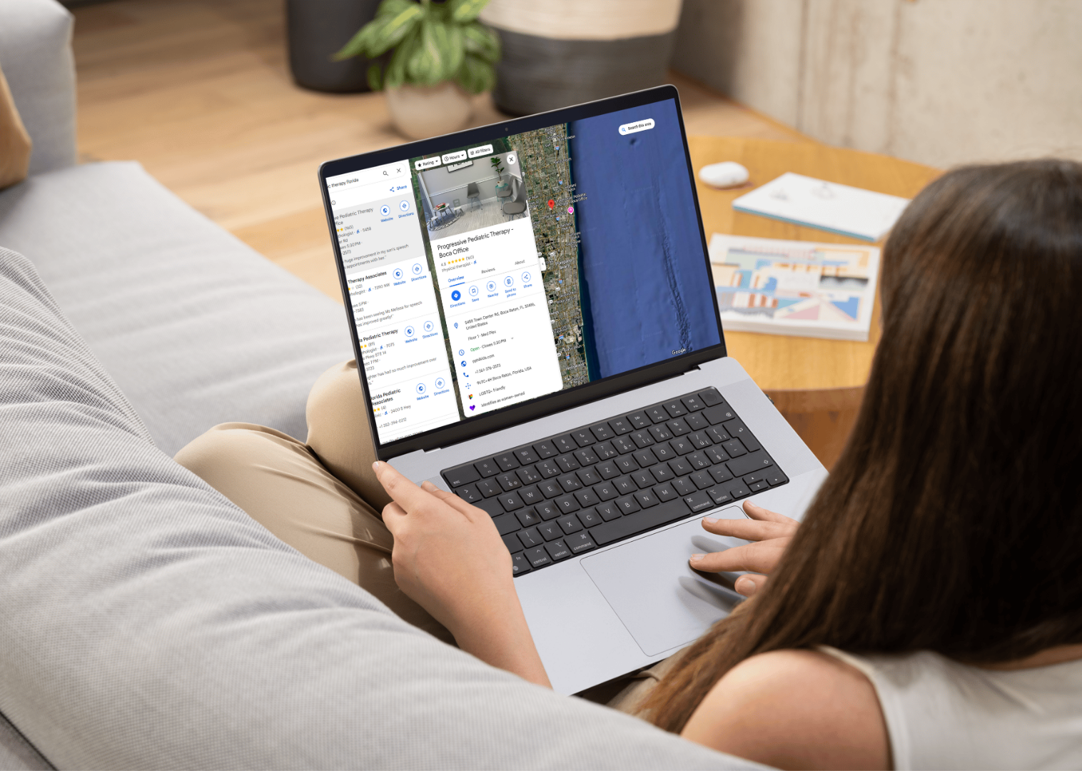 A woman is sitting on a couch using a laptop computer.