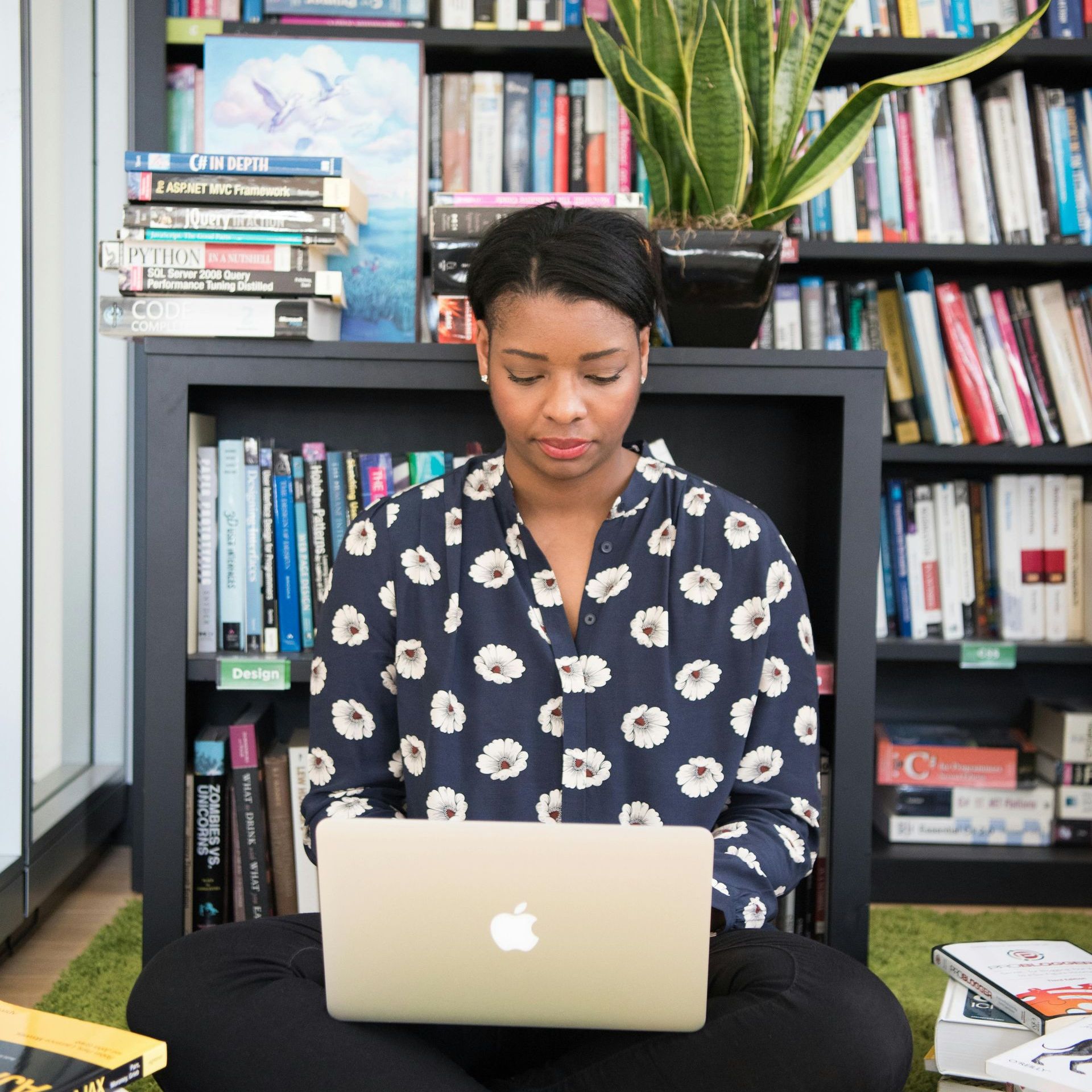 A woman is sitting on the floor using an apple laptop