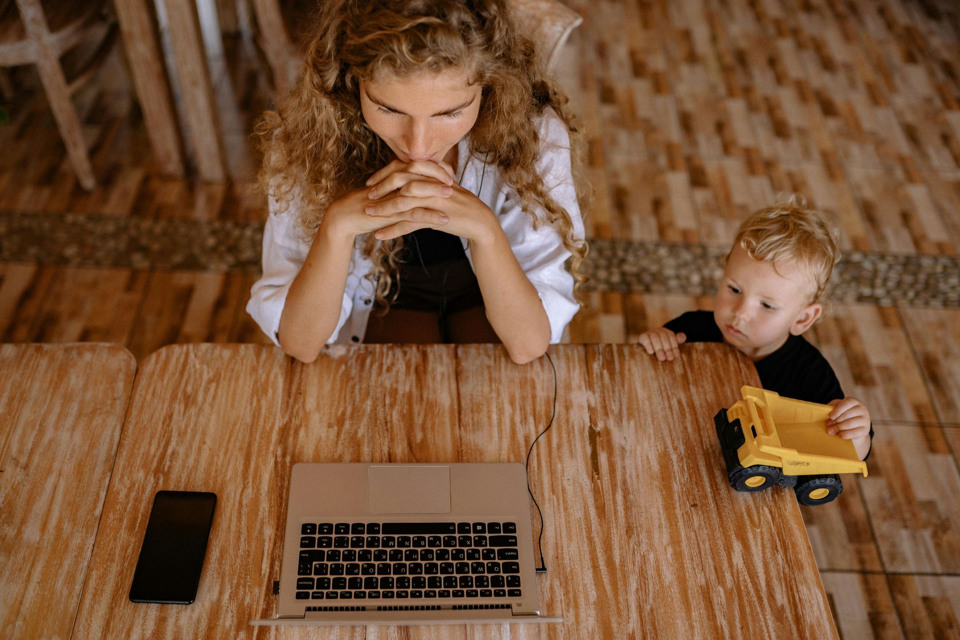 A woman is sitting at a table with a laptop and a child.