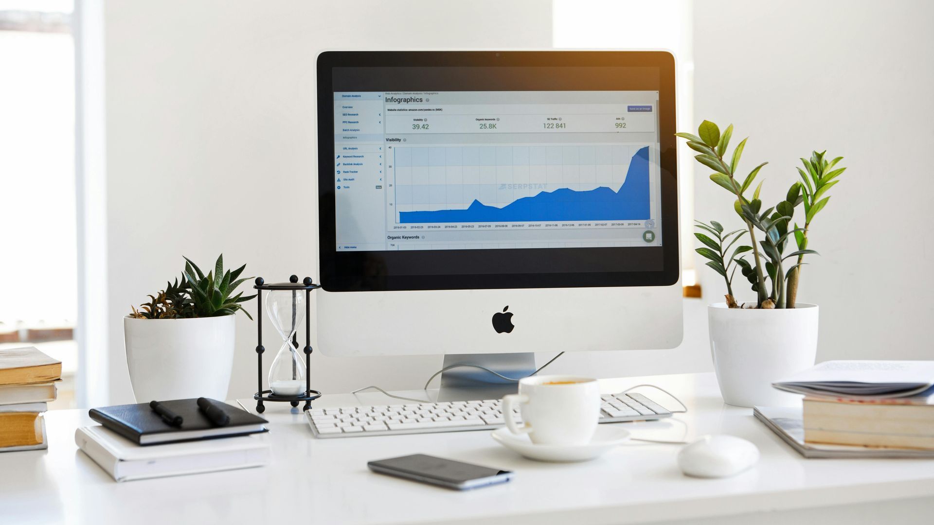 A computer monitor is sitting on a desk next to a plant.
