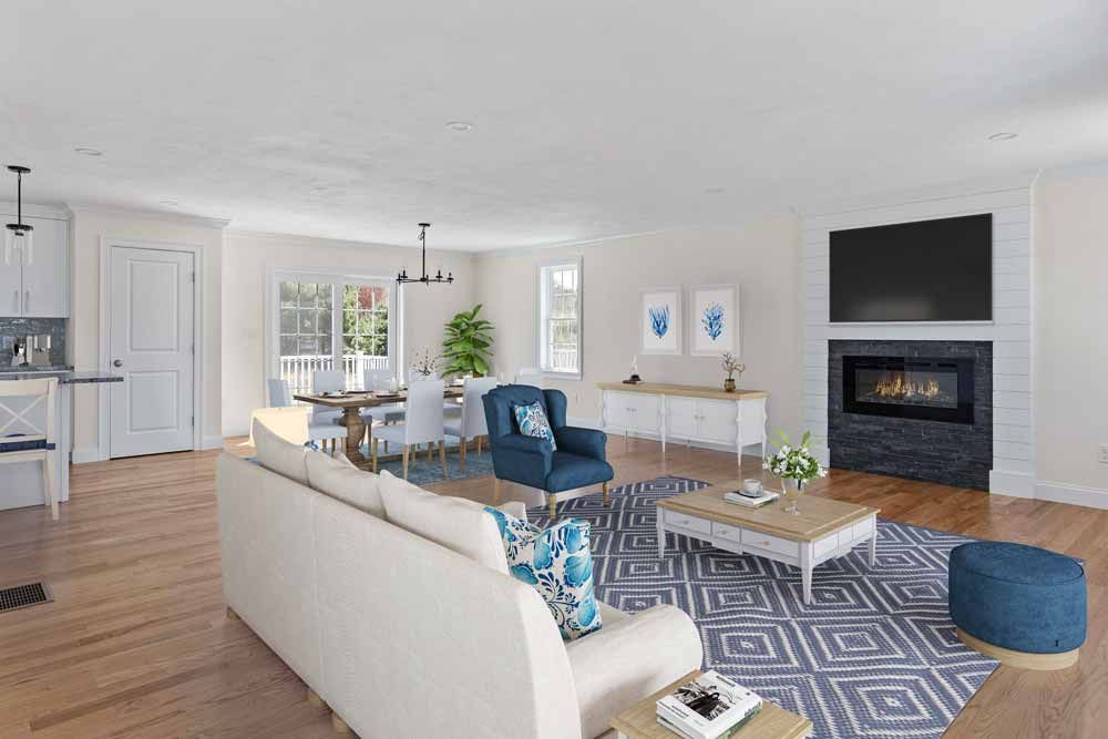 Bright open living room with white sofas, blue chairs, fireplace, and hardwood floors with a patterned rug