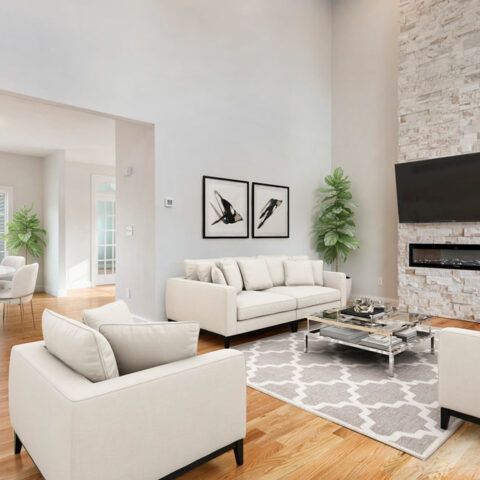 Bright modern living room with white sofas, gray rug, wall art, and stone fireplace
