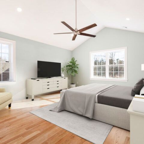 Bright modern bedroom with a gray bed, white dresser, TV, windows, and ceiling fan on hardwood floors