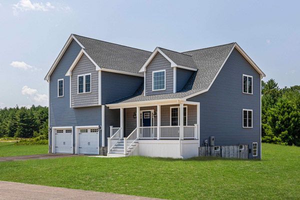 Gray two-story house with white trim, front porch, and attached two-car garage on a grassy lawn