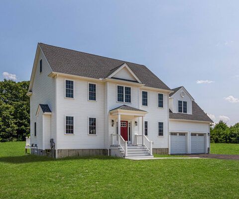White two-story suburban house with a red front door, white trim, and attached two-car garage on a green lawn