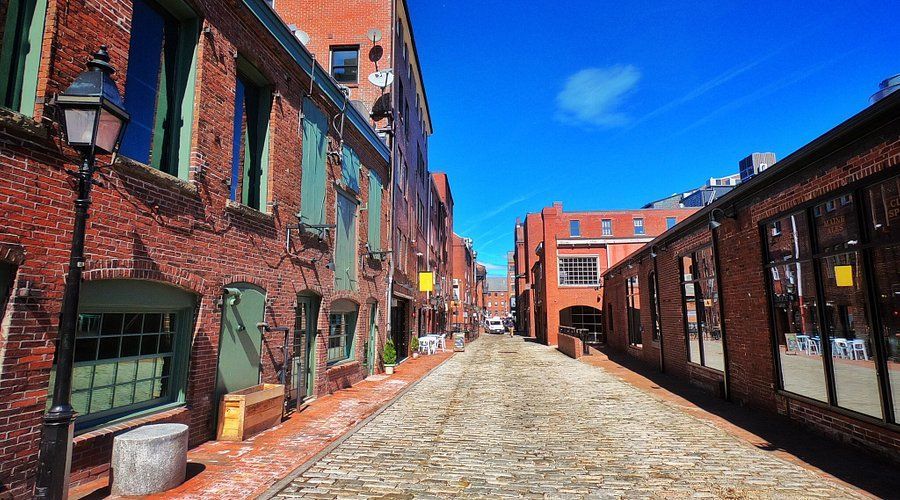 A cobblestone street between two brick buildings on a sunny day.