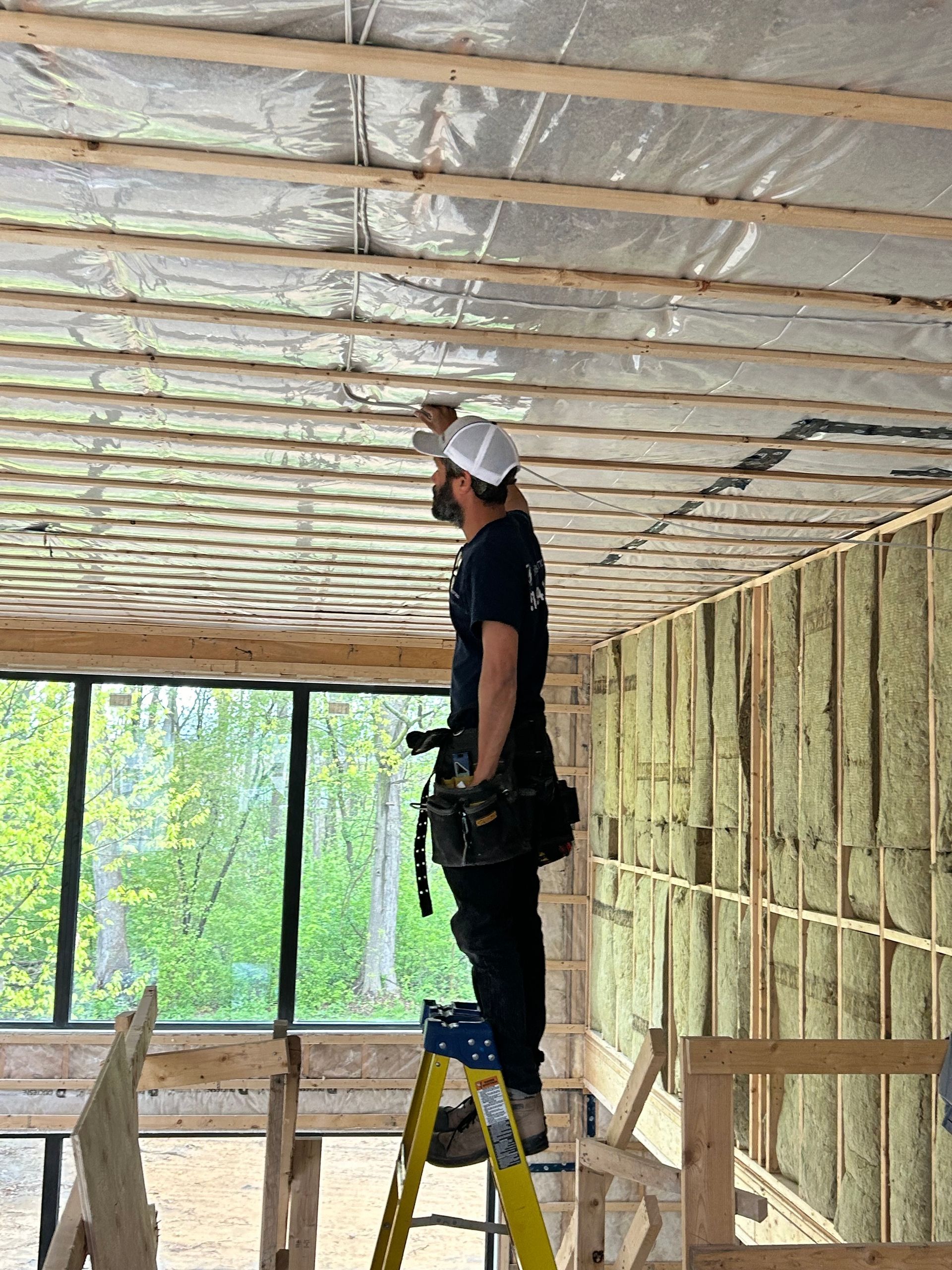 Un homme se tient debout sur une échelle dans une pièce en construction.