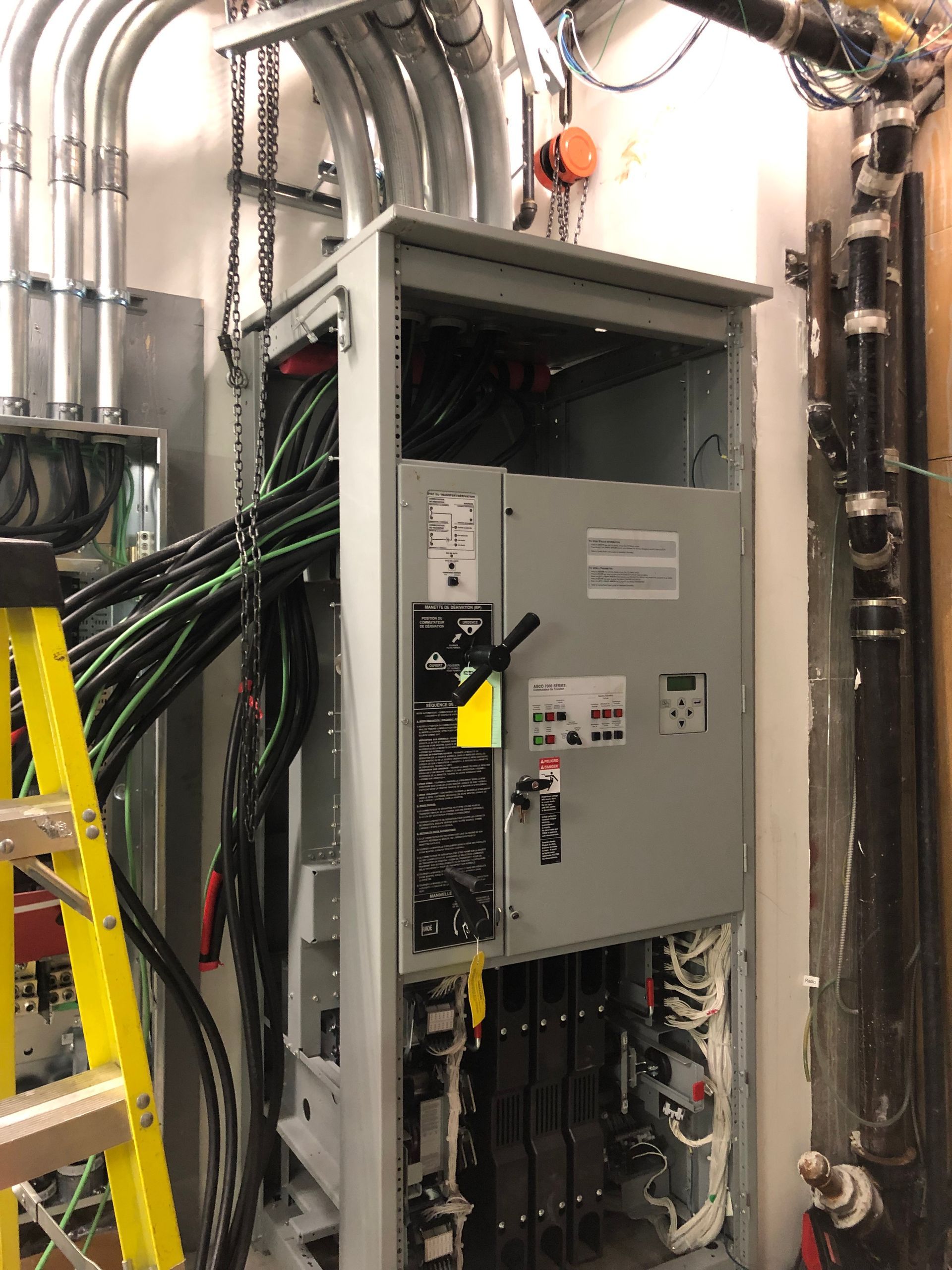 Une échelle se trouve à côté d'un grand boîtier électrique.