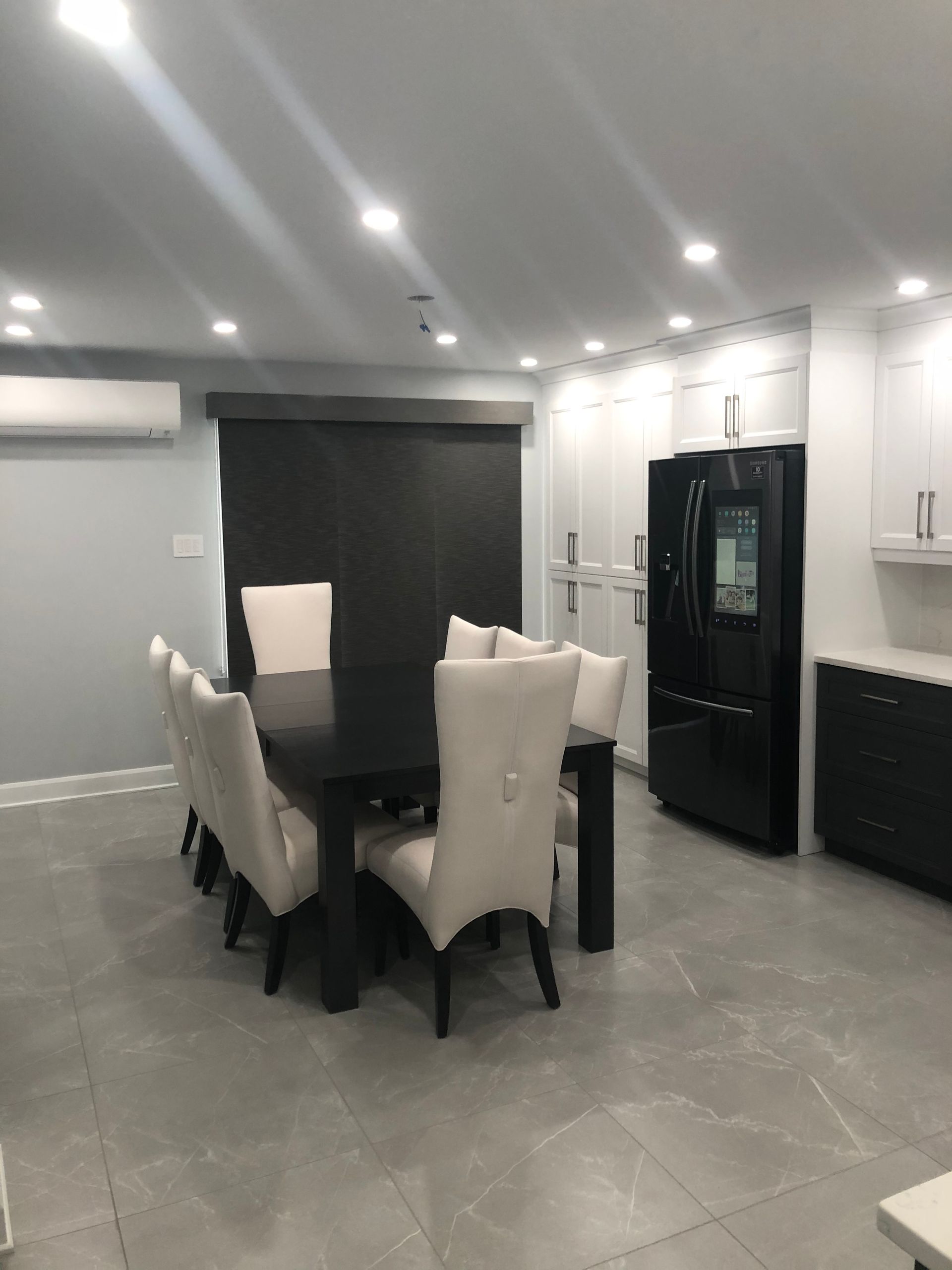 Une salle à manger avec une table, des chaises et un réfrigérateur