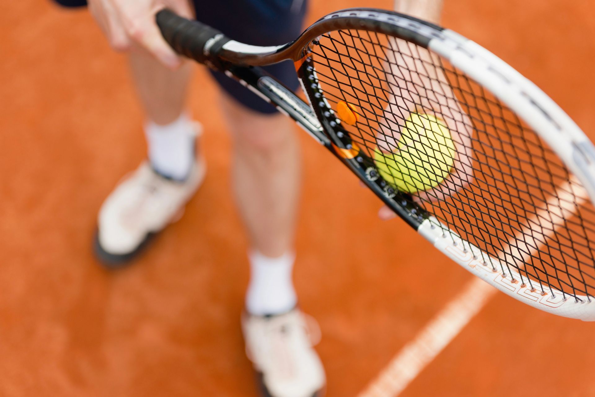 Giocatore di tennis che tiene in mano una racchetta con la palla su un campo in terra battuta.