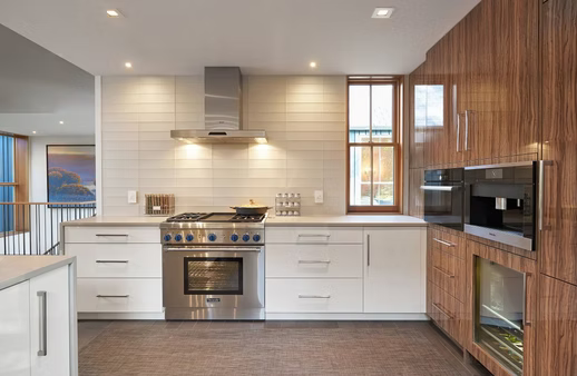Modern kitchen with white cabinets, wood accent wall, stainless steel stove, and large windows