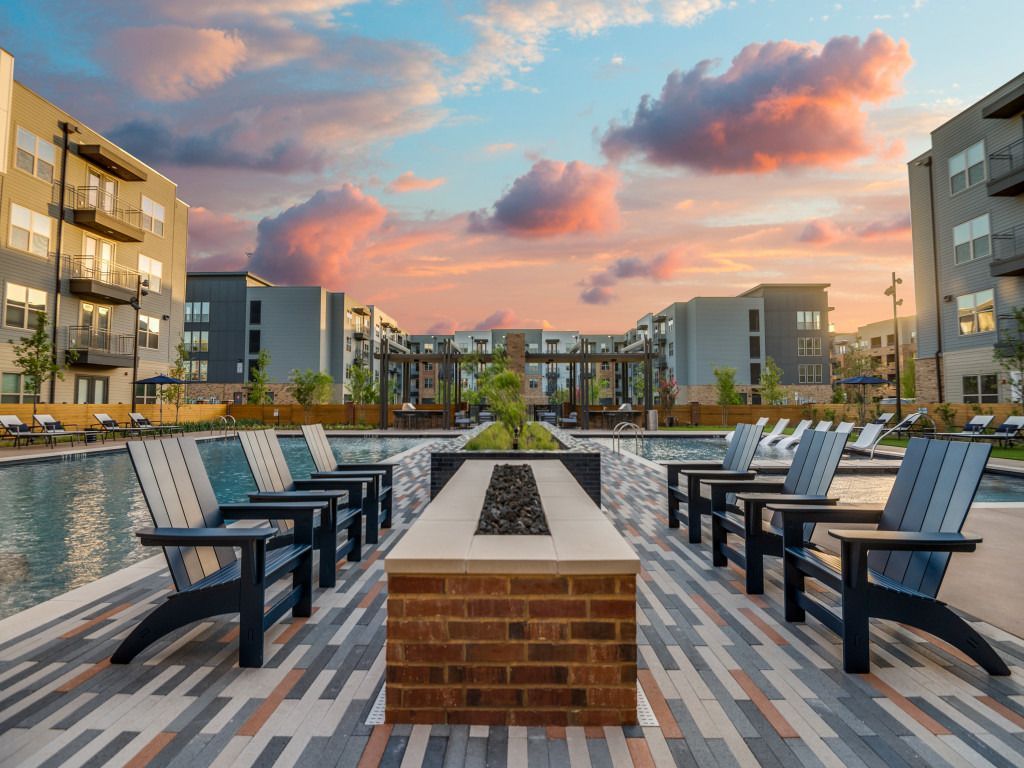 A fire pit surrounded by chairs next to a pool.