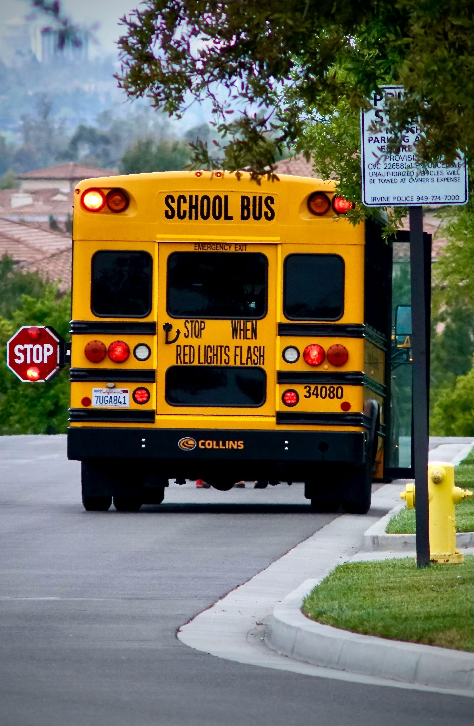 Yellow school bus driving away on a suburban street near a stop sign