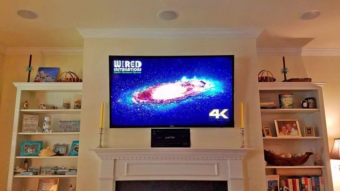 Living room with a wall-mounted TV displaying a colorful galaxy on a white mantel fireplace