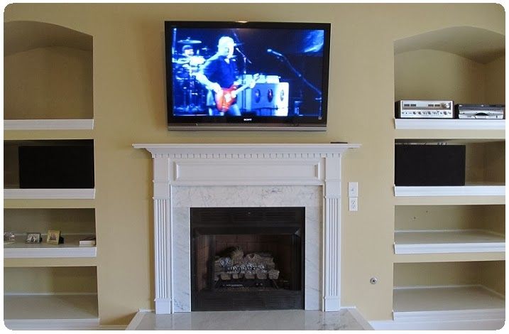 Living room with wall-mounted TV above a white fireplace and built-in shelves on both sides