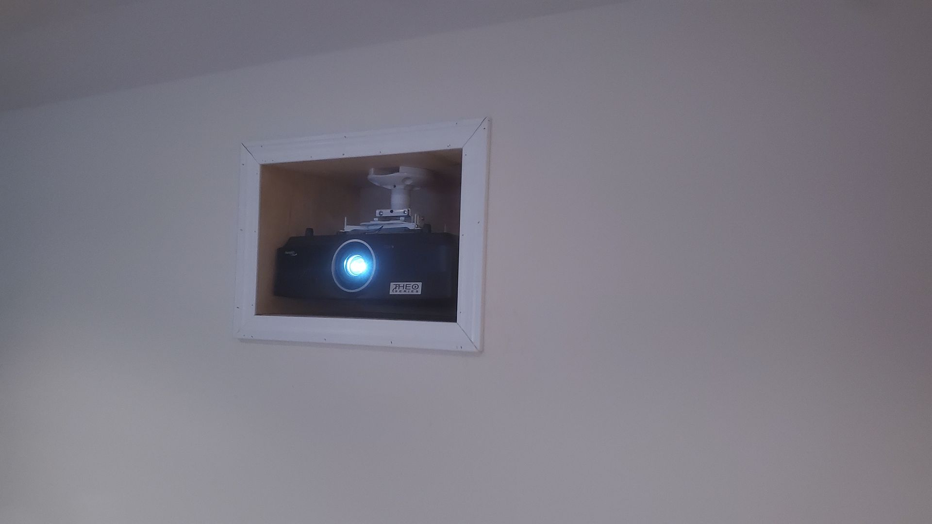 Wall-mounted white-framed box with a blue light glowing inside a wall opening