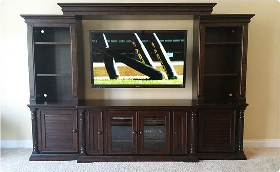Dark wood entertainment center with a TV in the middle and cabinets and shelves on both sides
