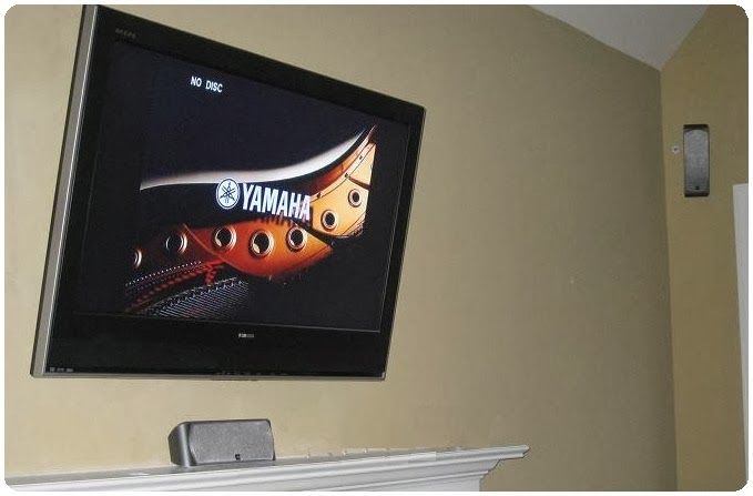 Wall-mounted TV on a beige wall above a mantel, showing the Transformers logo.