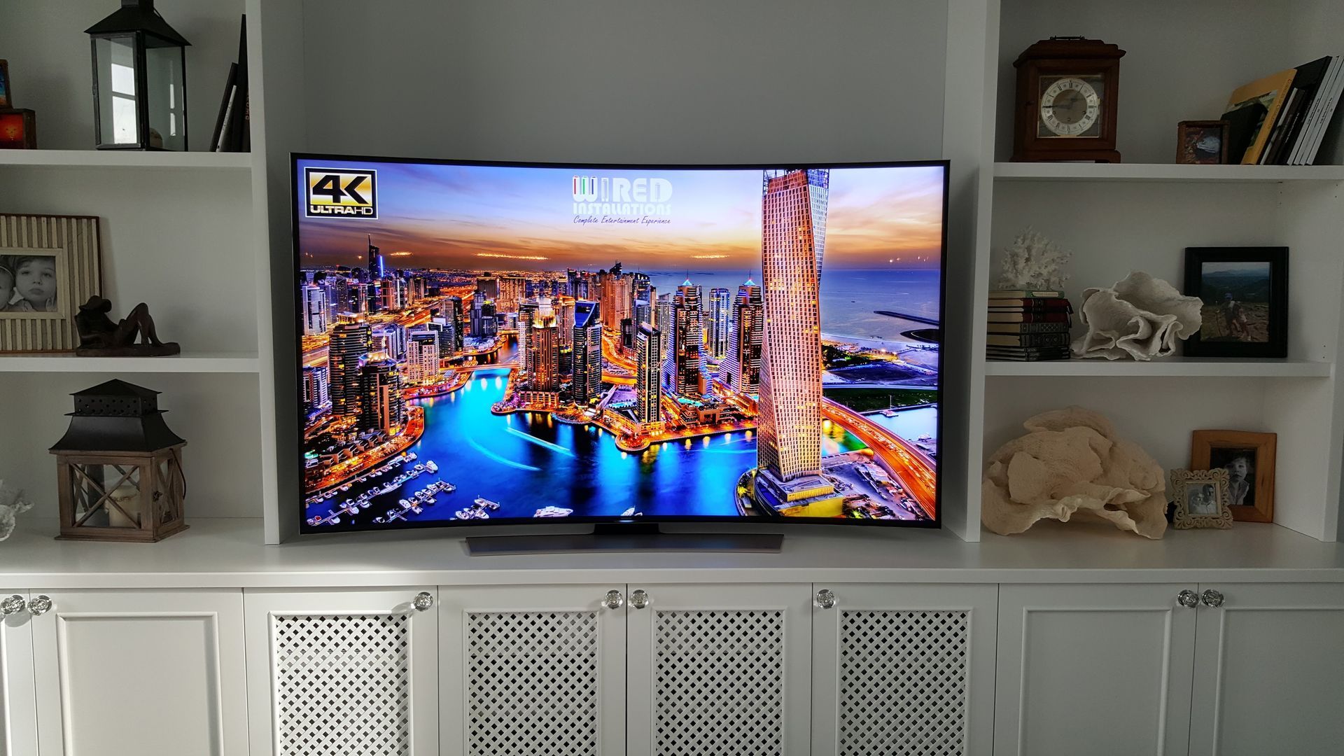 Living room with a wall-mounted TV showing a colorful city skyline at sunset
