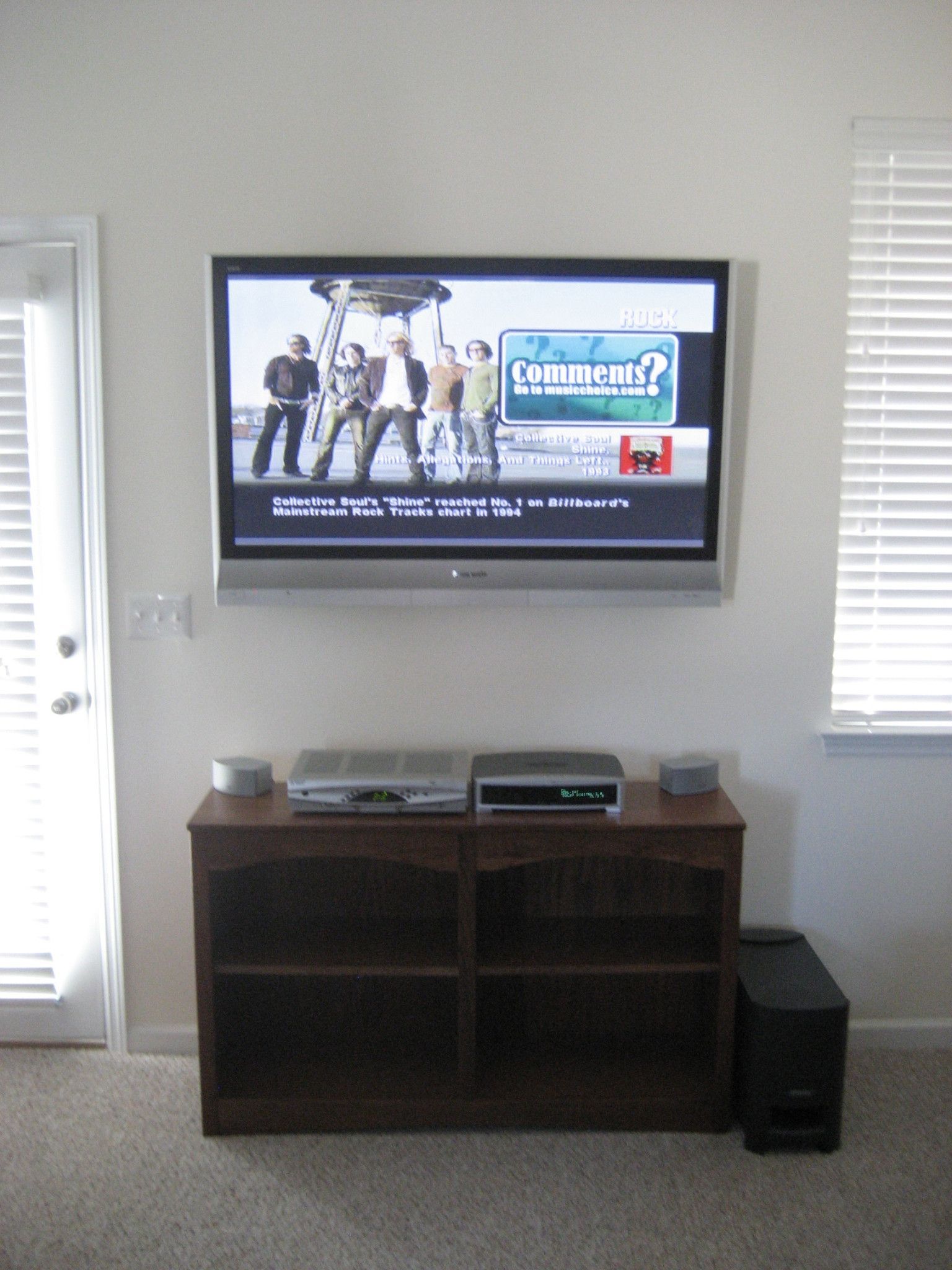 Living room with wall-mounted TV, media cabinet, and window blinds