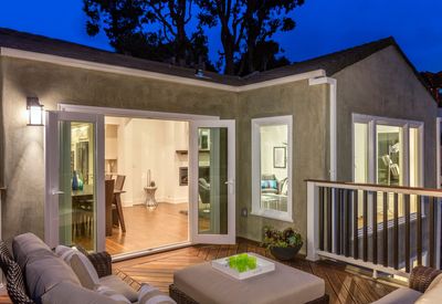 Modern patio with open French doors, warm interior lights, and outdoor seating at dusk